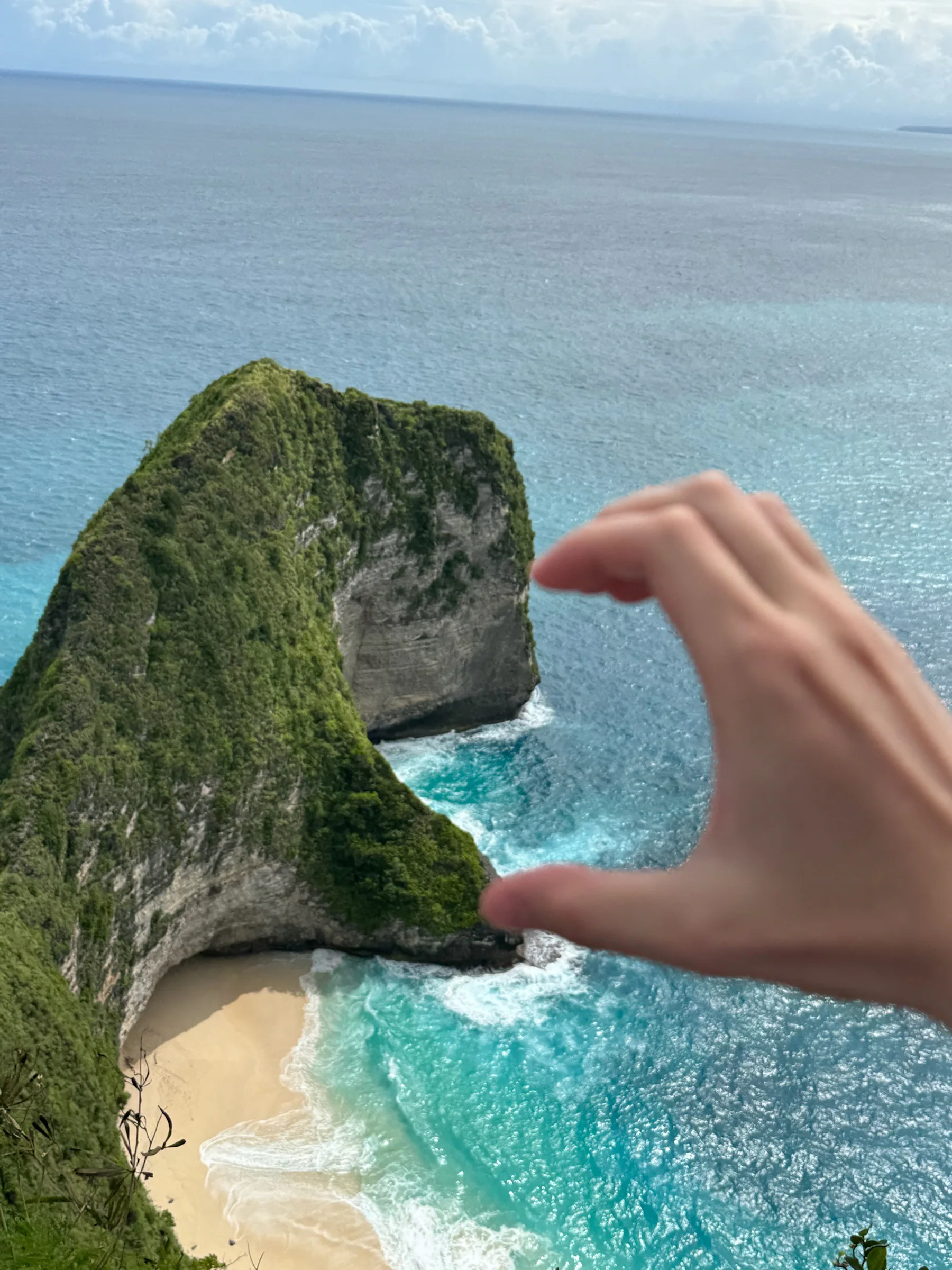 手与海岛形成错位构图的旅行照片